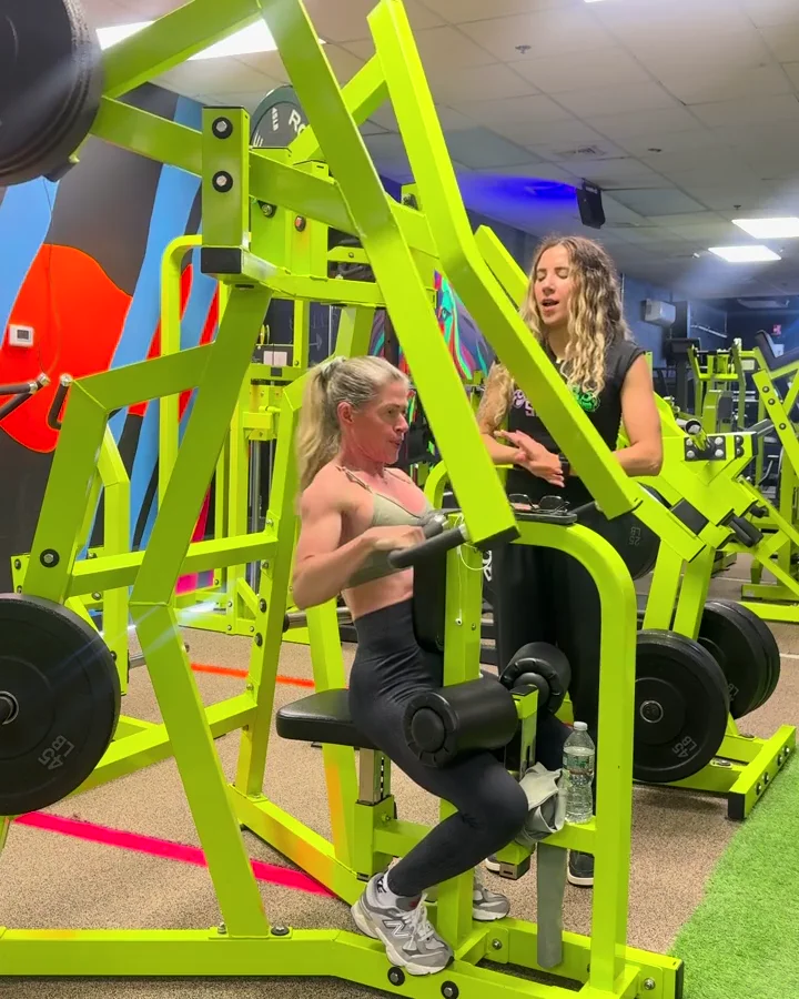 A coach guiding a member during a strength exercise at Power Shape